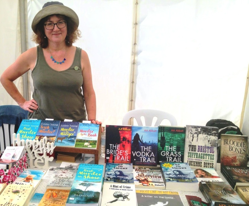 Debbie behind bookstall in khaki hat and vest