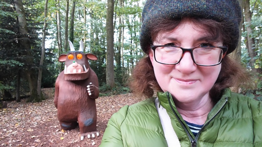 photo of Debbie Young in Harris Tweed hat with large sculpture of Gruffalo behind her