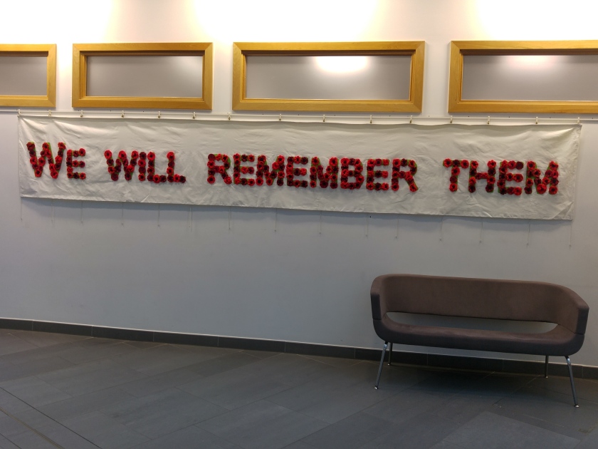 banner on wall with "we will remember them" spelled out in knitted poppies
